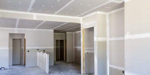 Interior of a new home under construction with the sheetrock up and the mudding and taping done
