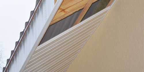 Eave of a house with white vinyl soffit and fascia being installed
